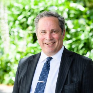 Mark Potter standing in front of blurred green background, smiling