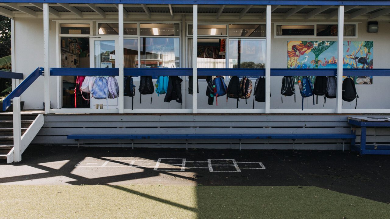 Primary school building verandah with school bags hanging on hooks.