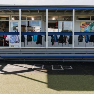 Primary school building verandah with school bags hanging on hooks.